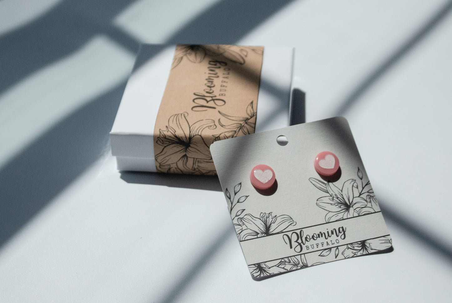 pink circle stud earrings with white heart design on Blooming Buffalo branded earring card