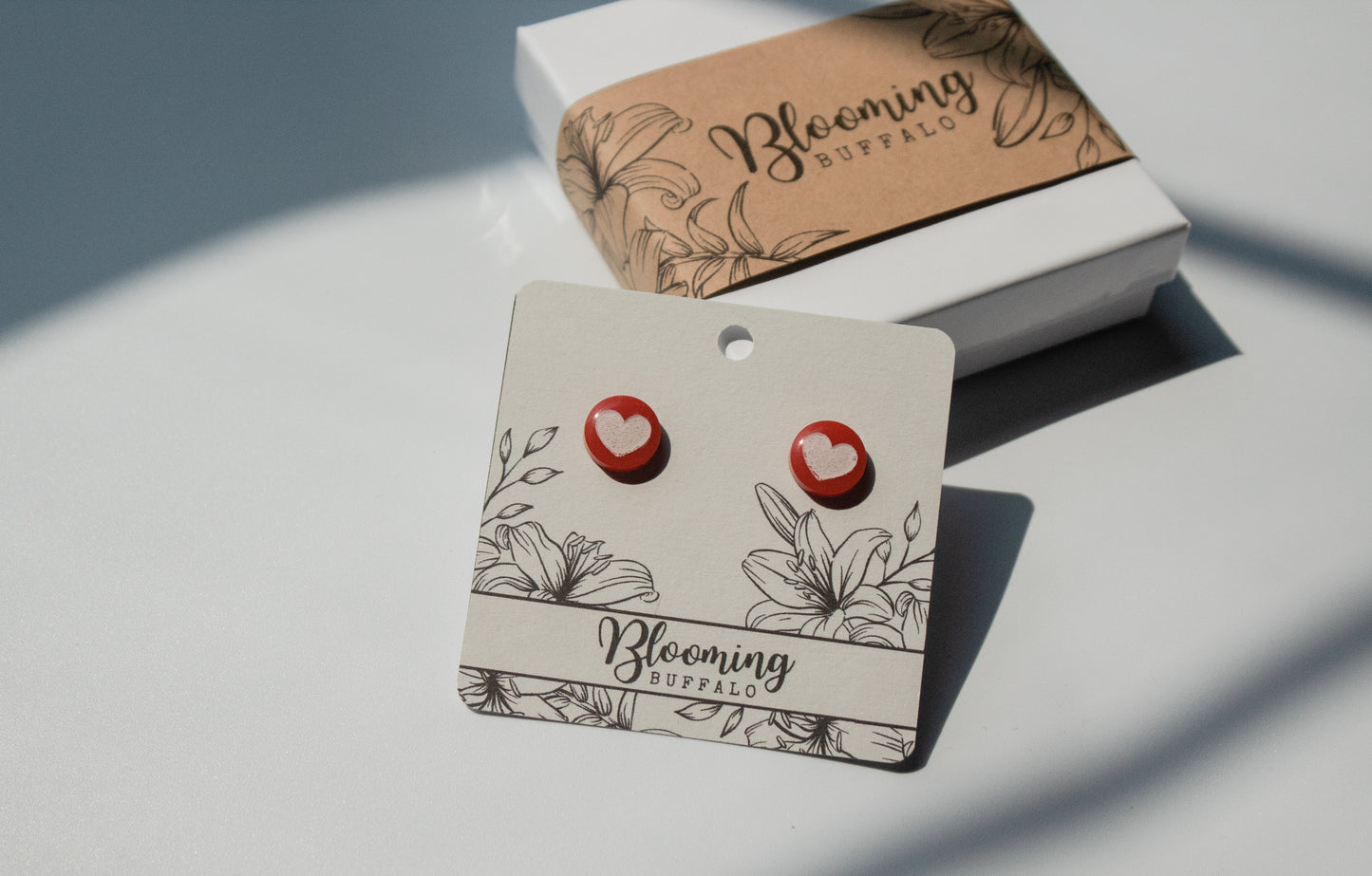 red circle stud earrings with white heart design on Blooming Buffalo branded earring card
