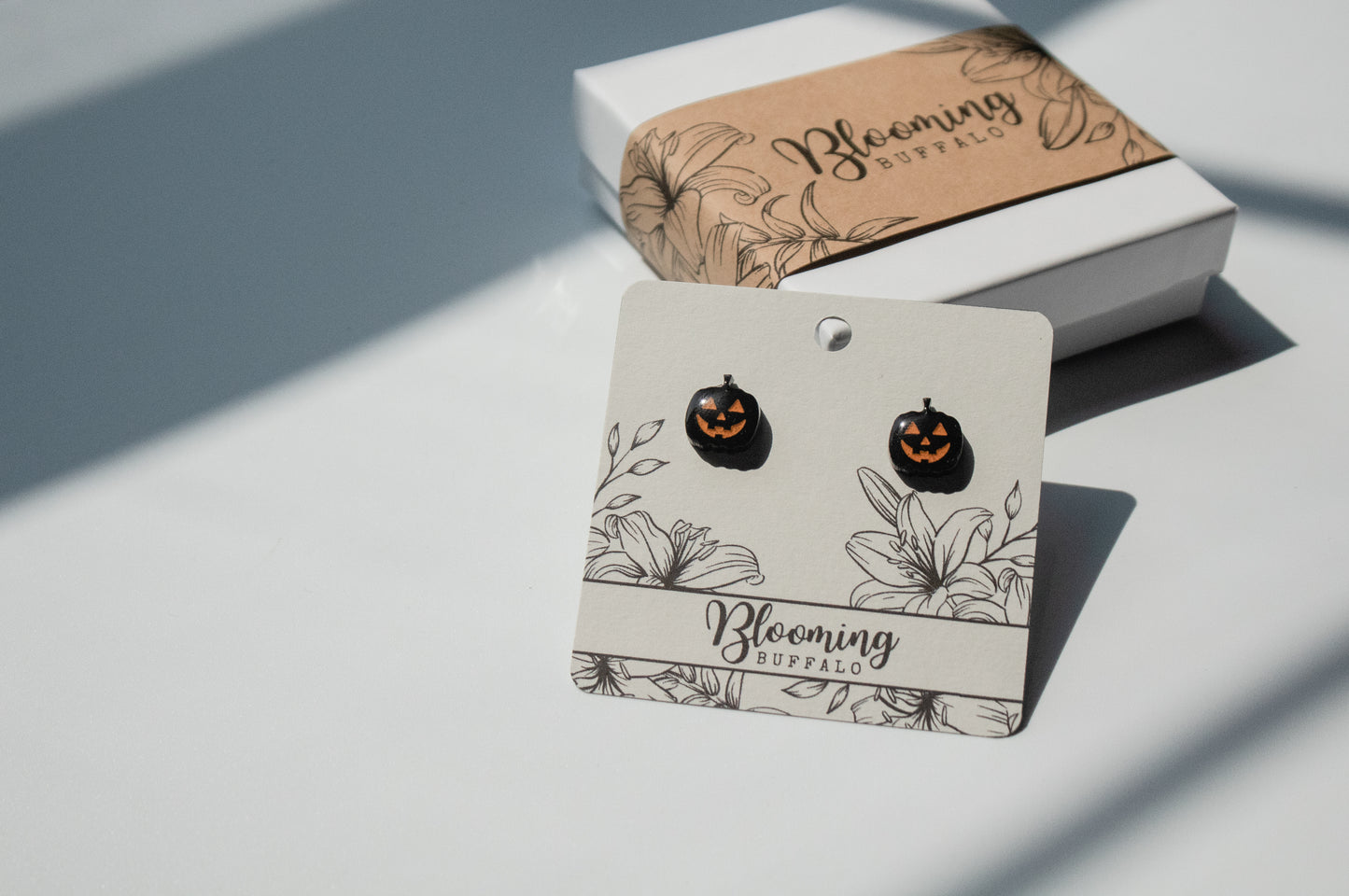 Black and orange spooky jack-o-lantern halloween stud earrings on Blooming Buffalo branded earring card