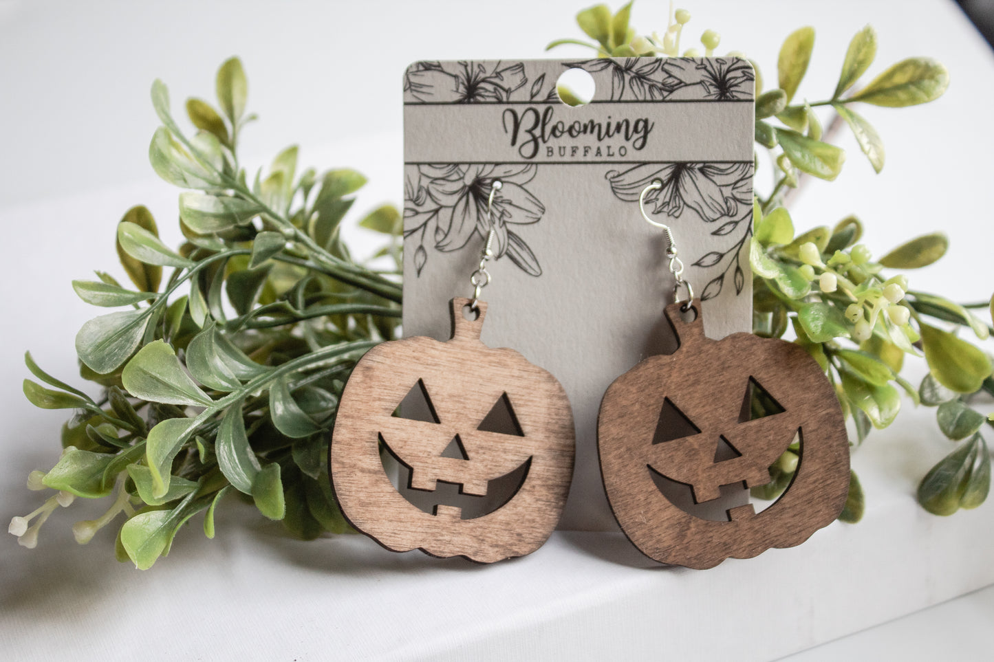 medium toned wood jack-o-lantern dangle earrings on a Blooming Buffalo branded earring card