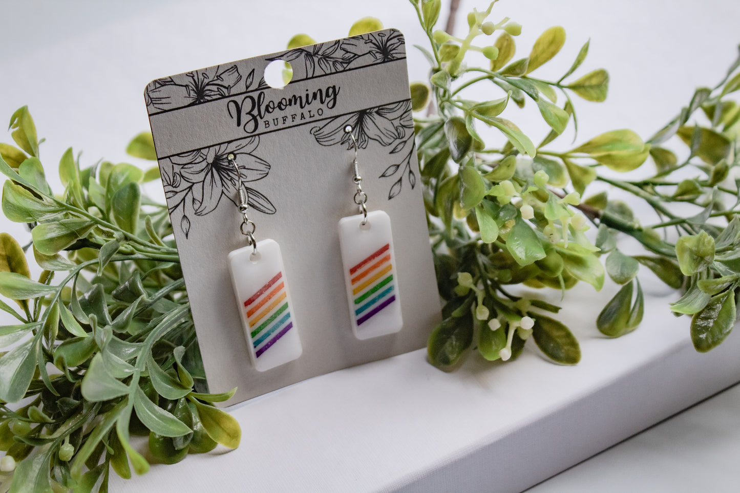white rectangle dangle earrings with rainbow stripes on Blooming Buffalo branded earring card