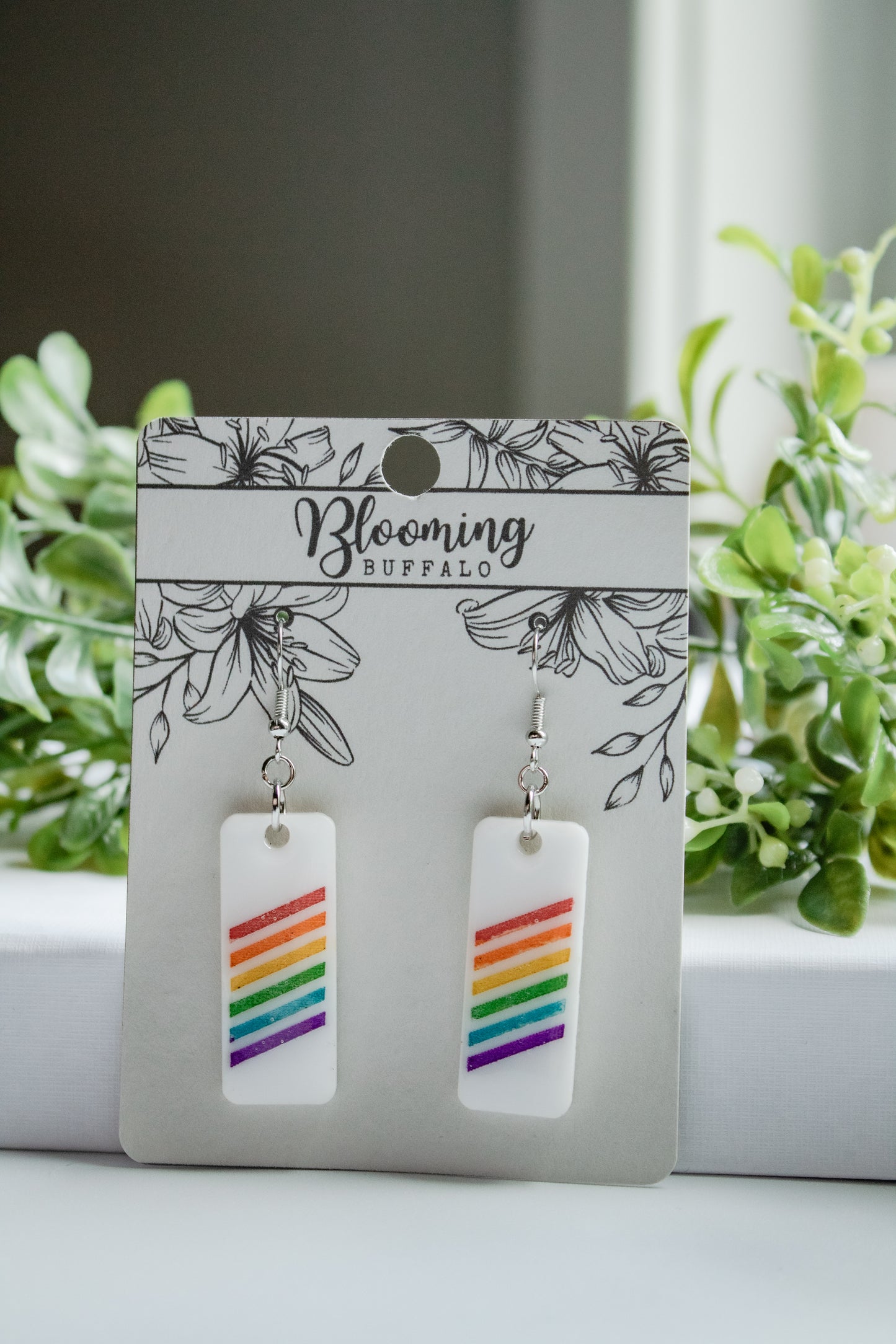 white rectangle dangle earrings with rainbow stripes on Blooming Buffalo branded earring card