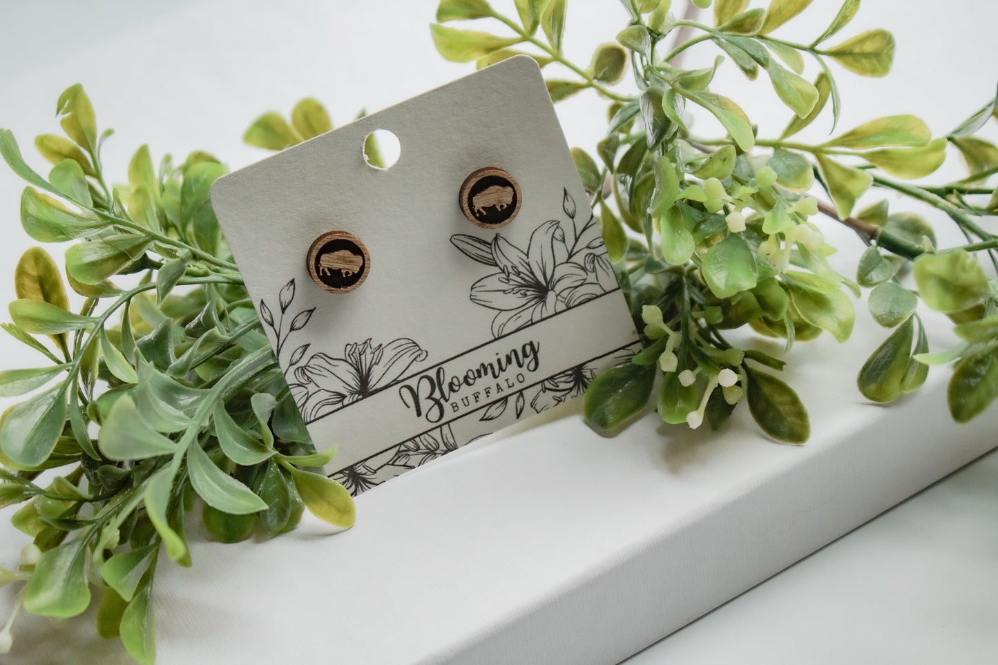 medium toned wood circle stud earrings with a buffalo design on a Blooming Buffalo branded earring card