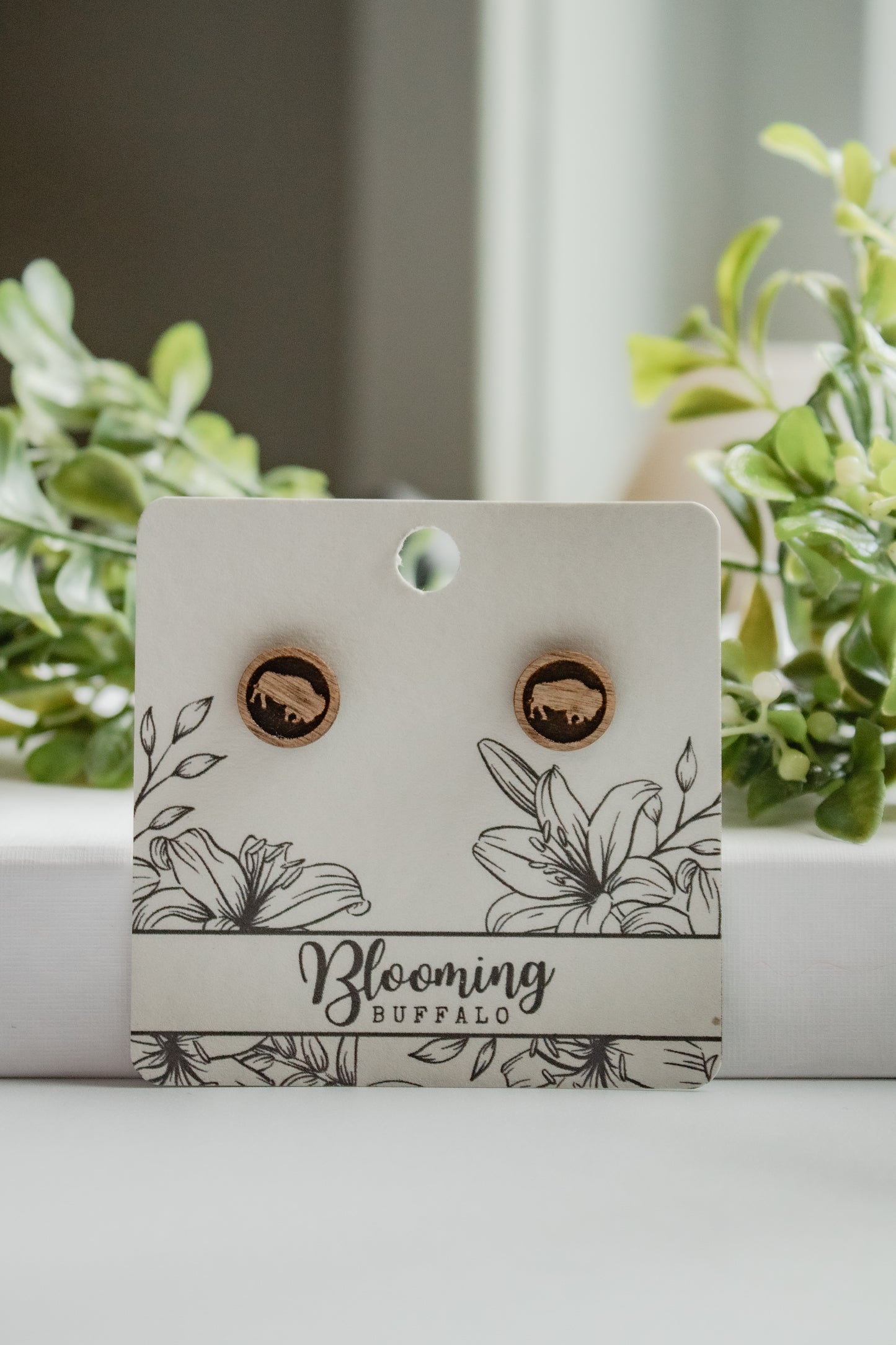 medium toned wood circle stud earrings with a buffalo design on a Blooming Buffalo branded earring card