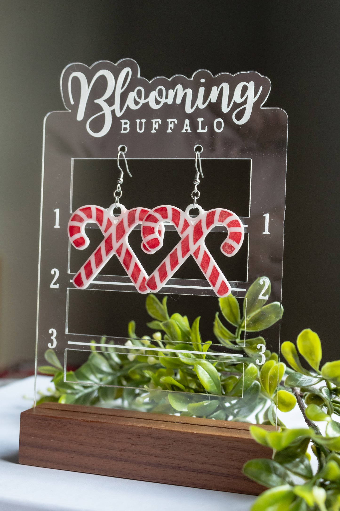 Red and white crossed candy cane dangle earrings that are about 2 inches tall including the wire