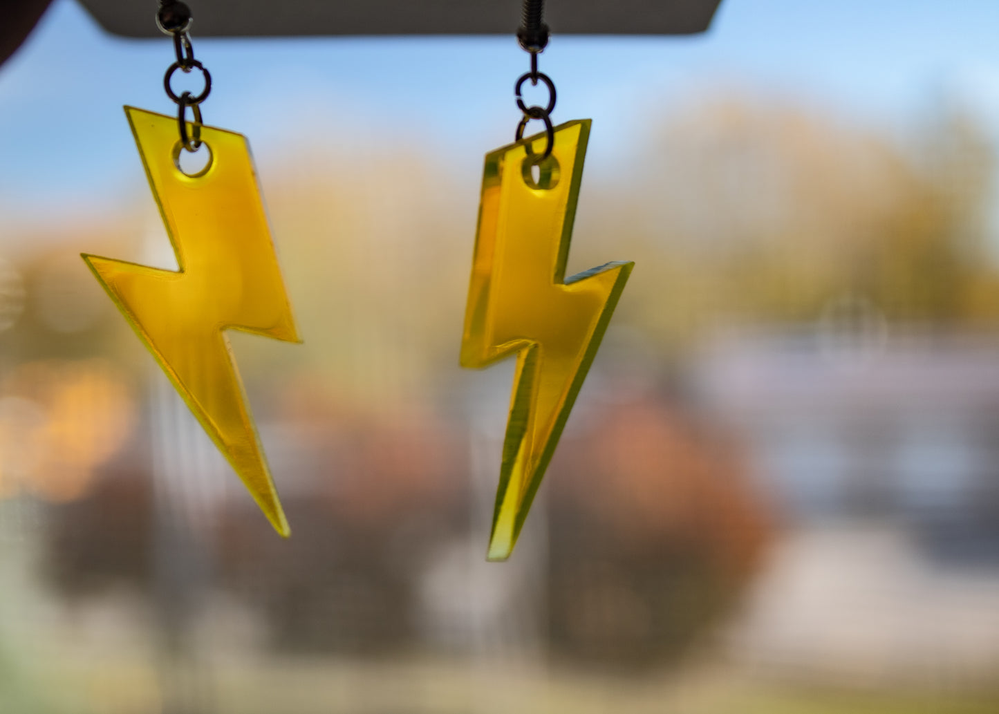 fluorescent yellow lightning bolt dangle earrings in front of window showing light shining through