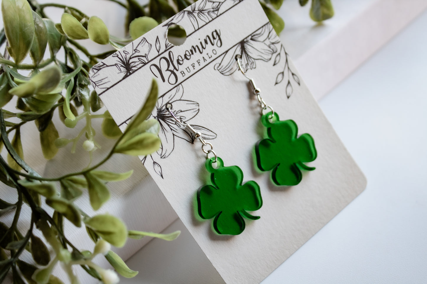 translucent green four-leaf clover shamrock dangle earrings on Blooming Buffalo branded earring card