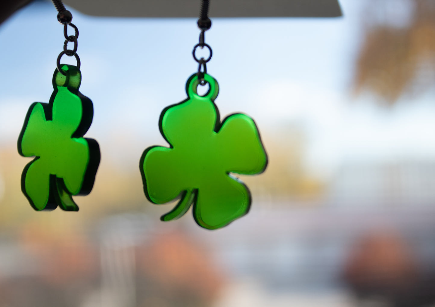 translucent green four-leaf clover shamrock dangle earrings in front of window to show light coming through
