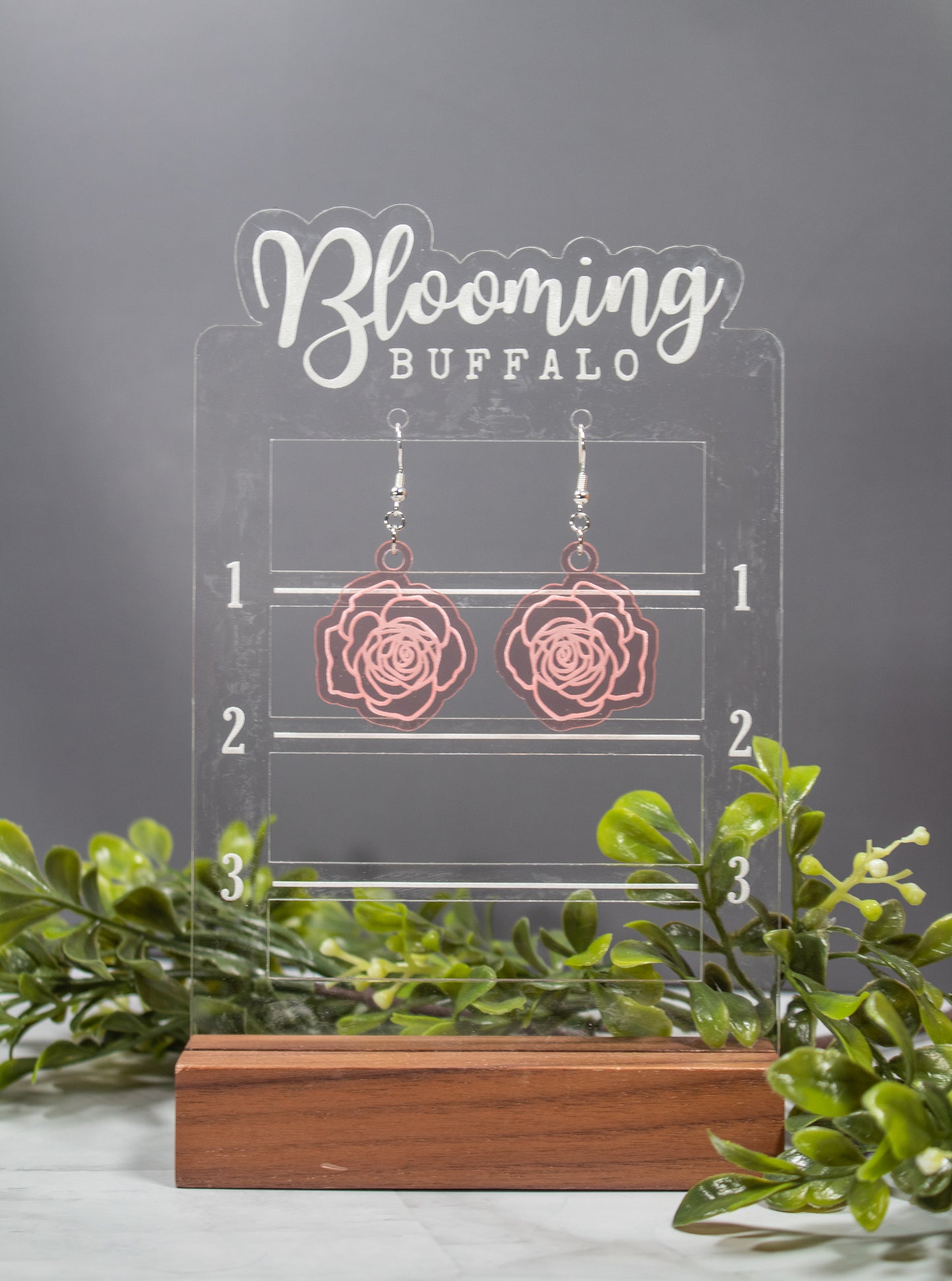 Translucent Rose Gold Acrylic Dangle Earrings shaped like roses with rose detail engraved. Earrings are on a Blooming Buffalo branded earring stand