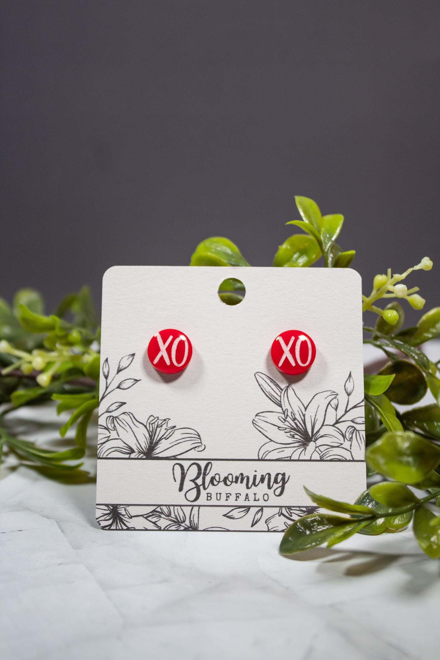 red circle stud earrings with a white XO design on a Blooming Buffalo branded earring card