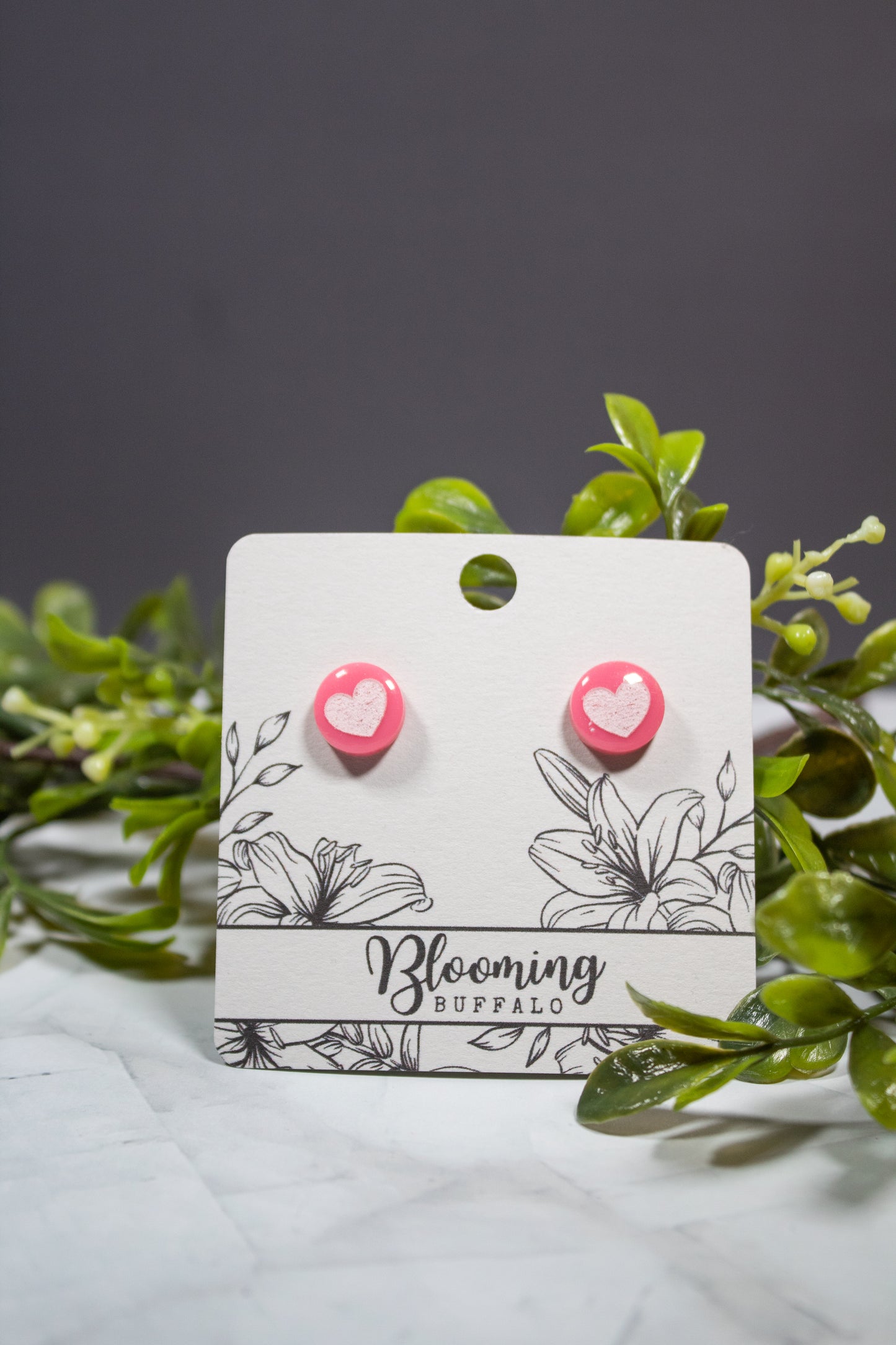 pink circle stud earrings with white heart design on Blooming Buffalo branded earring card