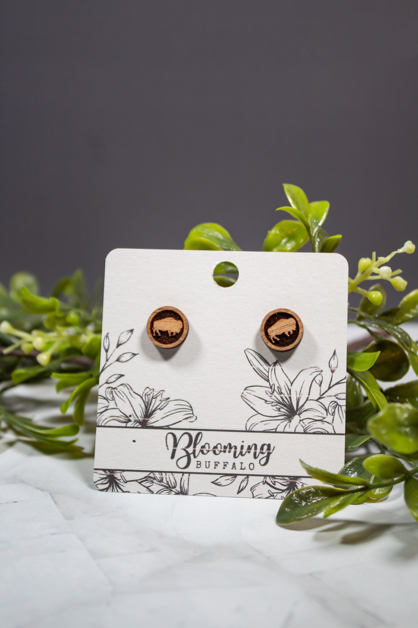 medium toned wood circle stud earrings with a buffalo design on a Blooming Buffalo branded earring card