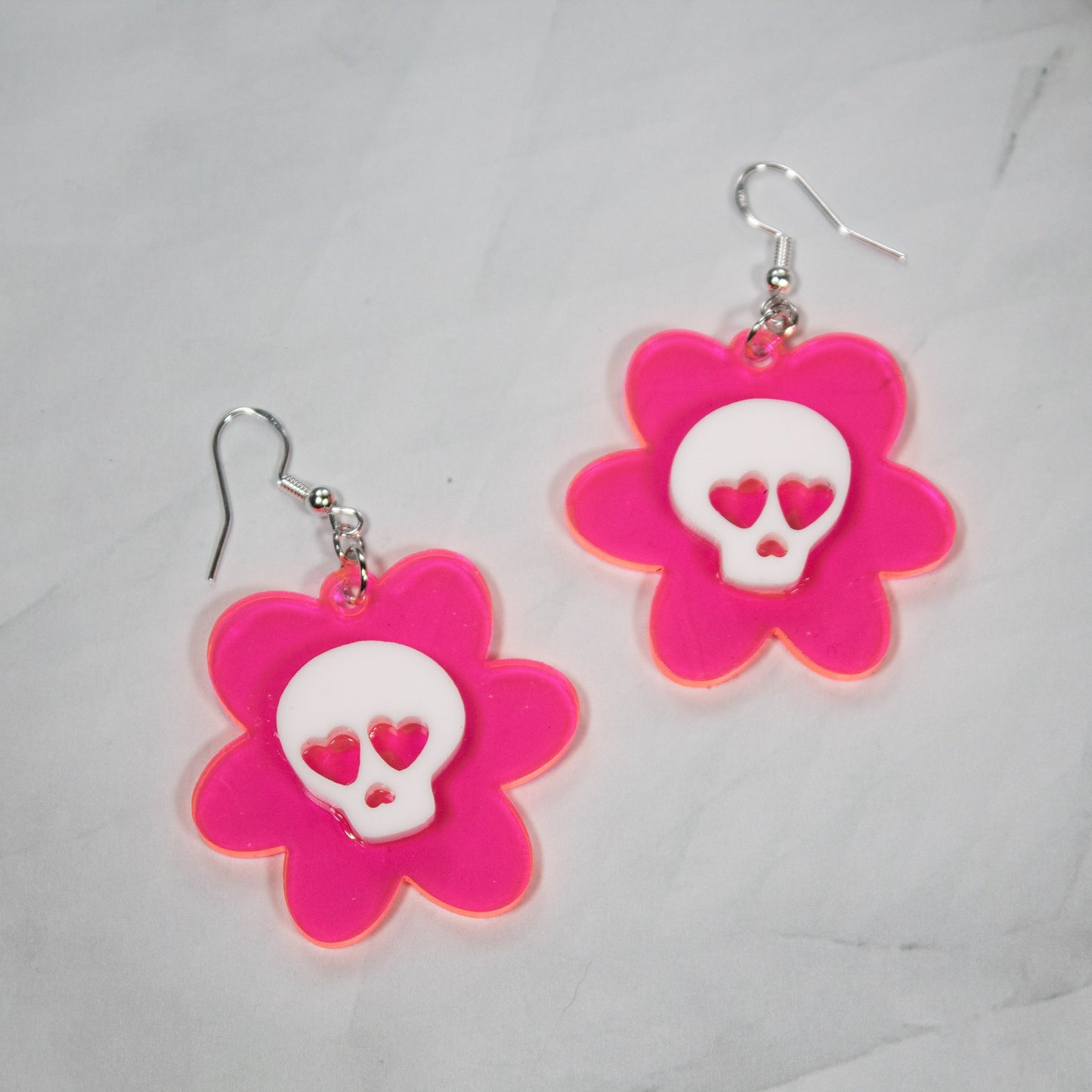 fluorescent hot pink flower dangle earrings. White skulls with heart eyes in the center