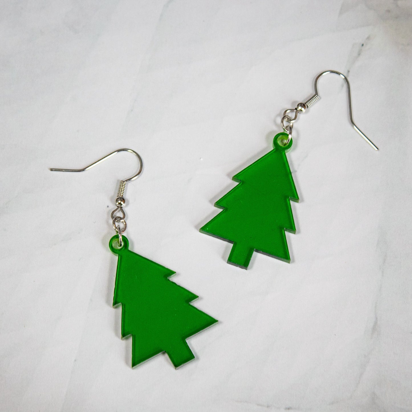 translucent green evergreen winter tree dangle earrings on white marble background