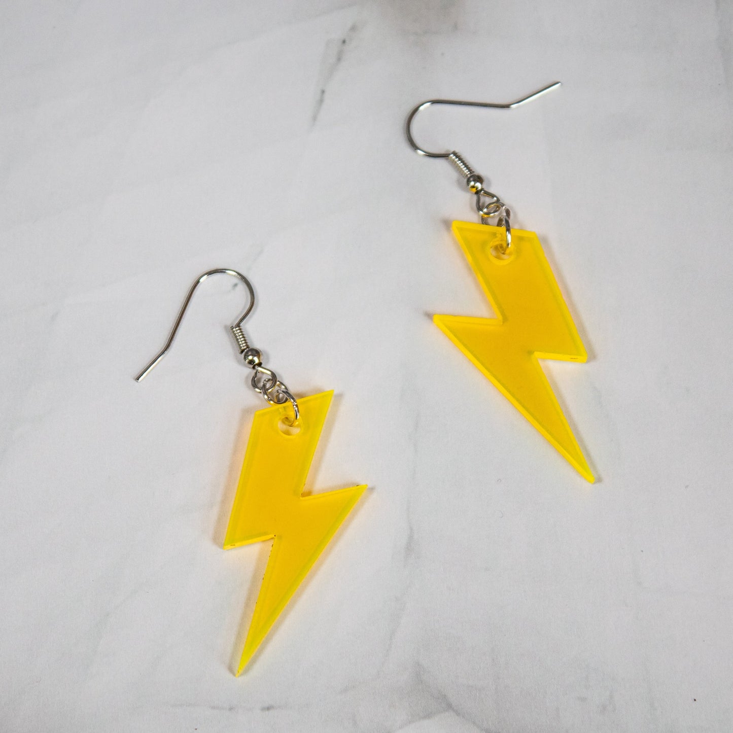 fluorescent yellow lightning bolt dangle earrings on white marble background