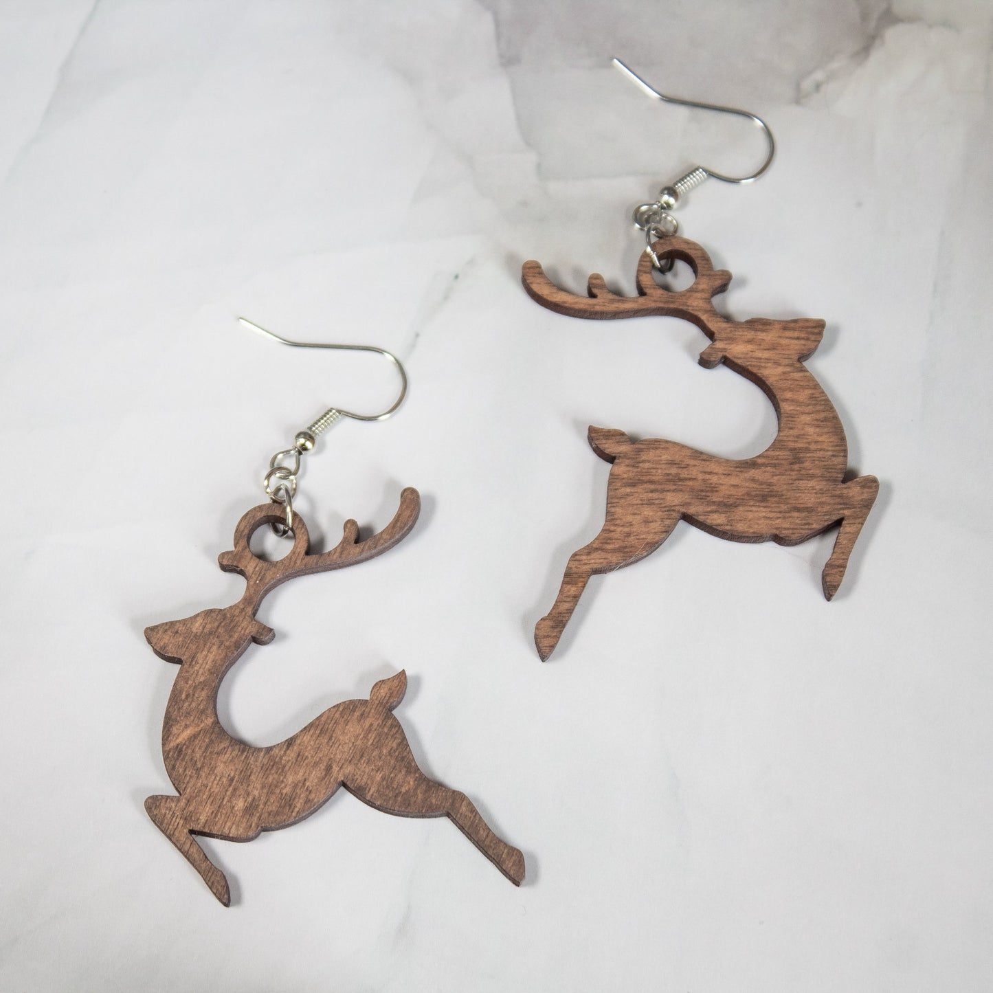 medium toned wooden reindeer dangle earrings on white marble background