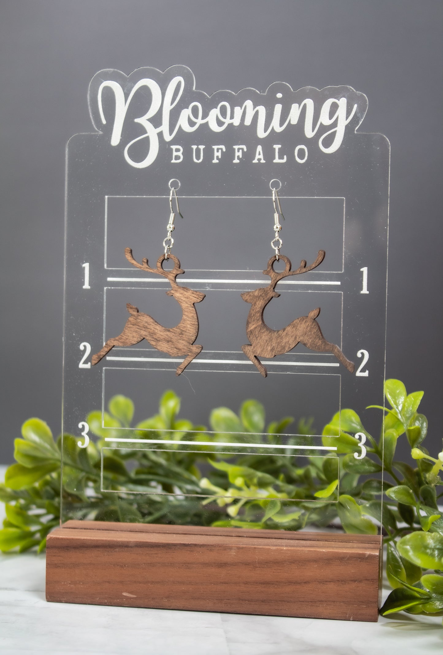 medium toned wooden reindeer dangle earrings on Blooming Buffalo branded earring stand