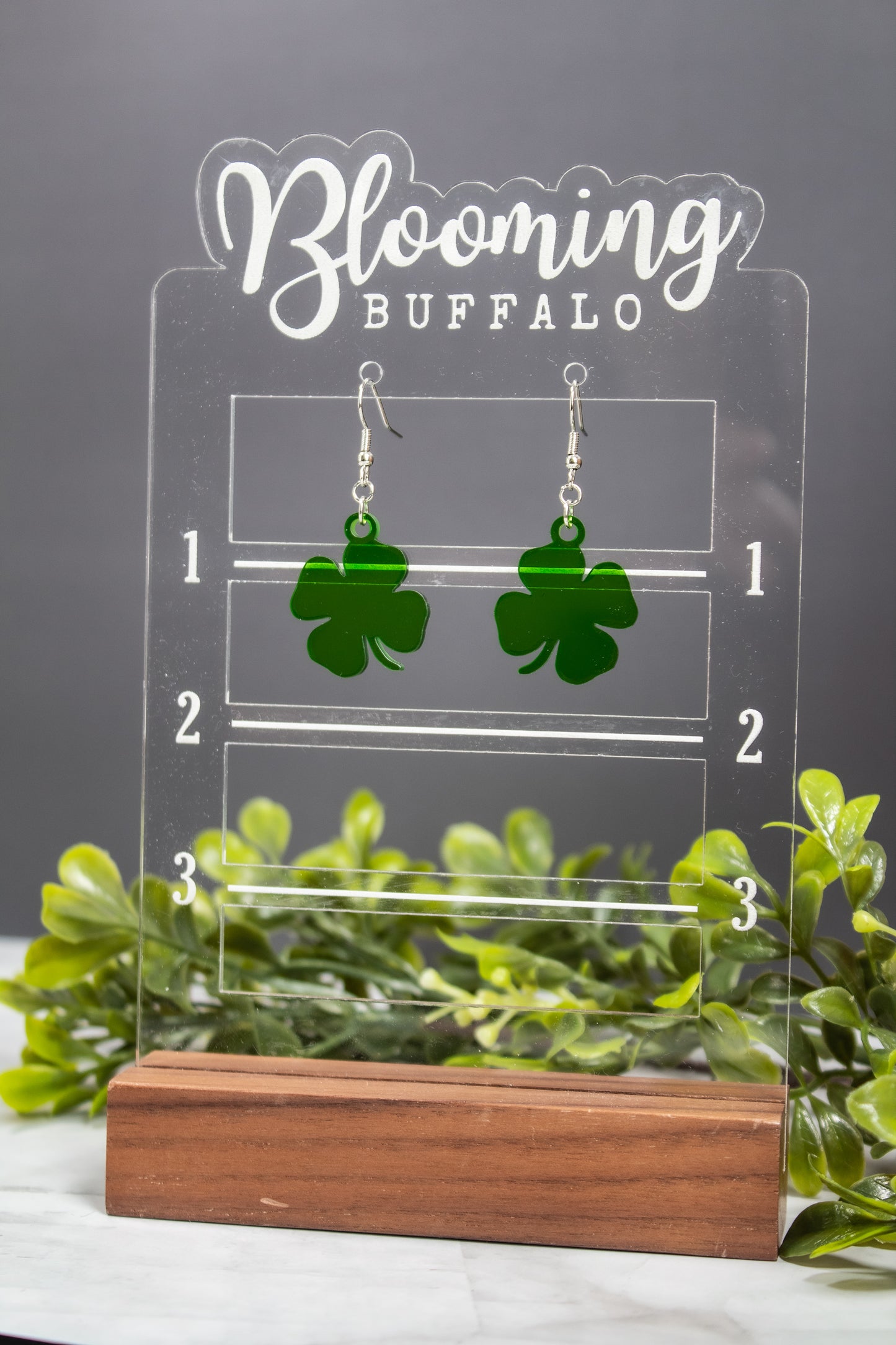 translucent green four-leaf clover shamrock dangle earrings on Blooming Buffalo branded earring stand