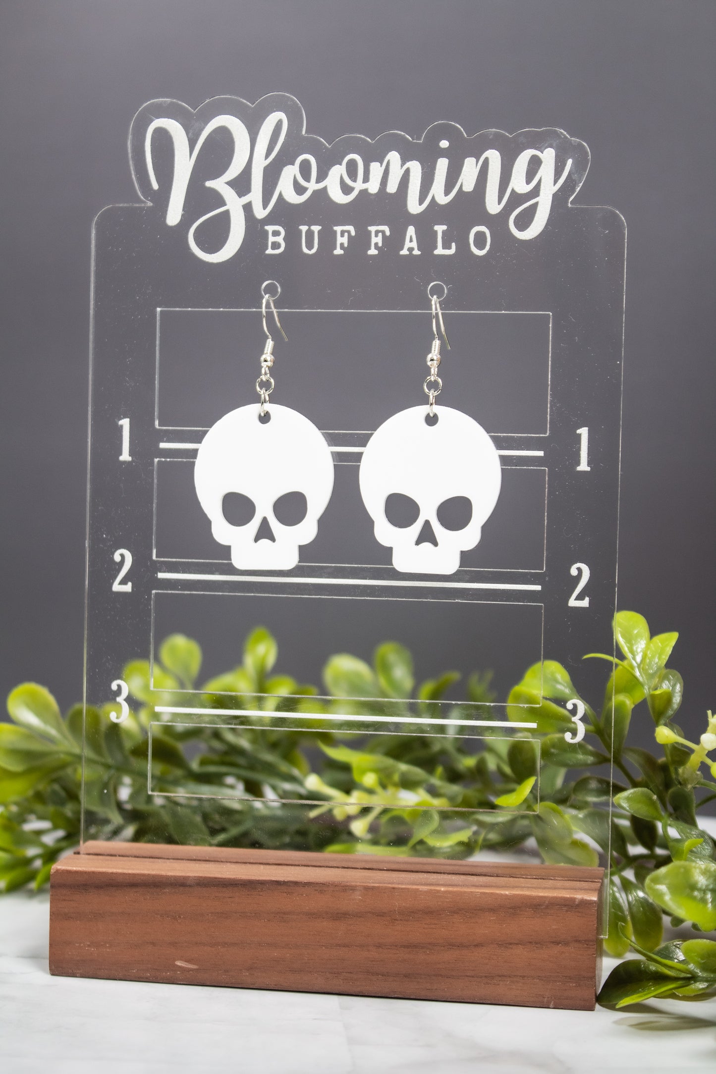 Large white skull dangle earrings on Blooming Buffalo branded earring stand