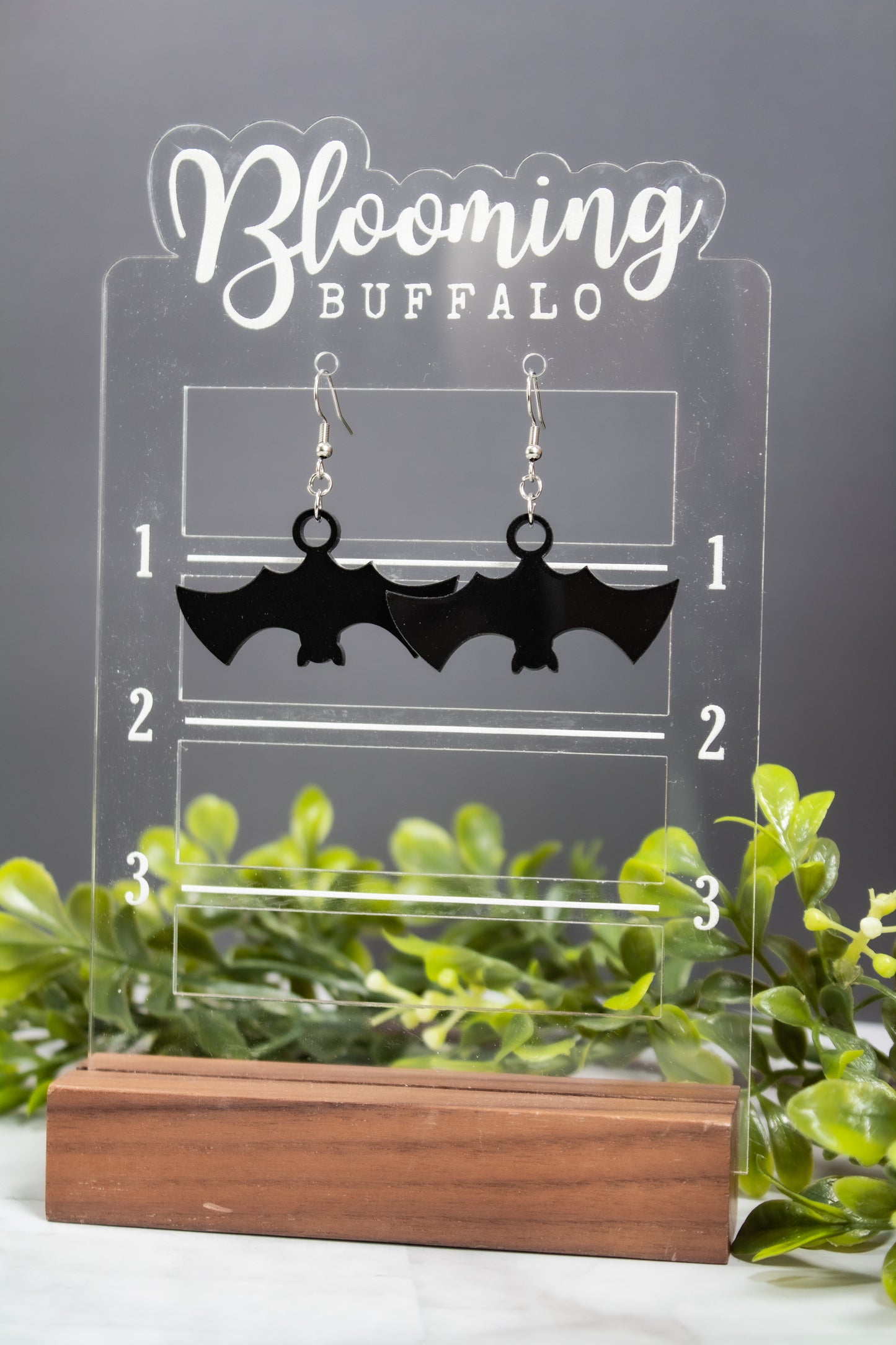 Spooky Halloween black bat dangle earrings on Blooming Buffalo branded stand