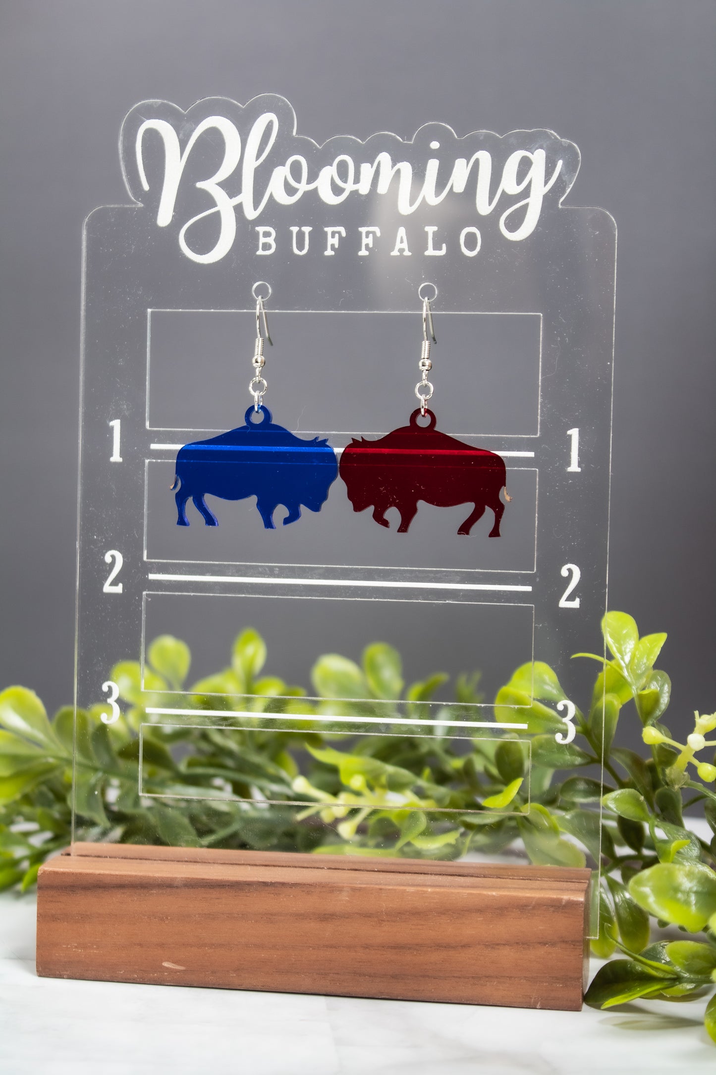 Translucent red and blue buffalo dangle earrings on a Blooming Buffalo branded earring stand