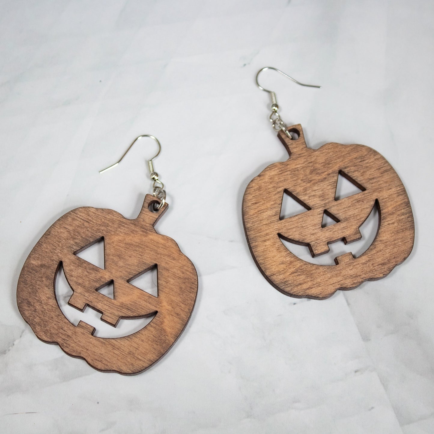 medium toned wood jack-o-lantern dangle earrings on a white marble background