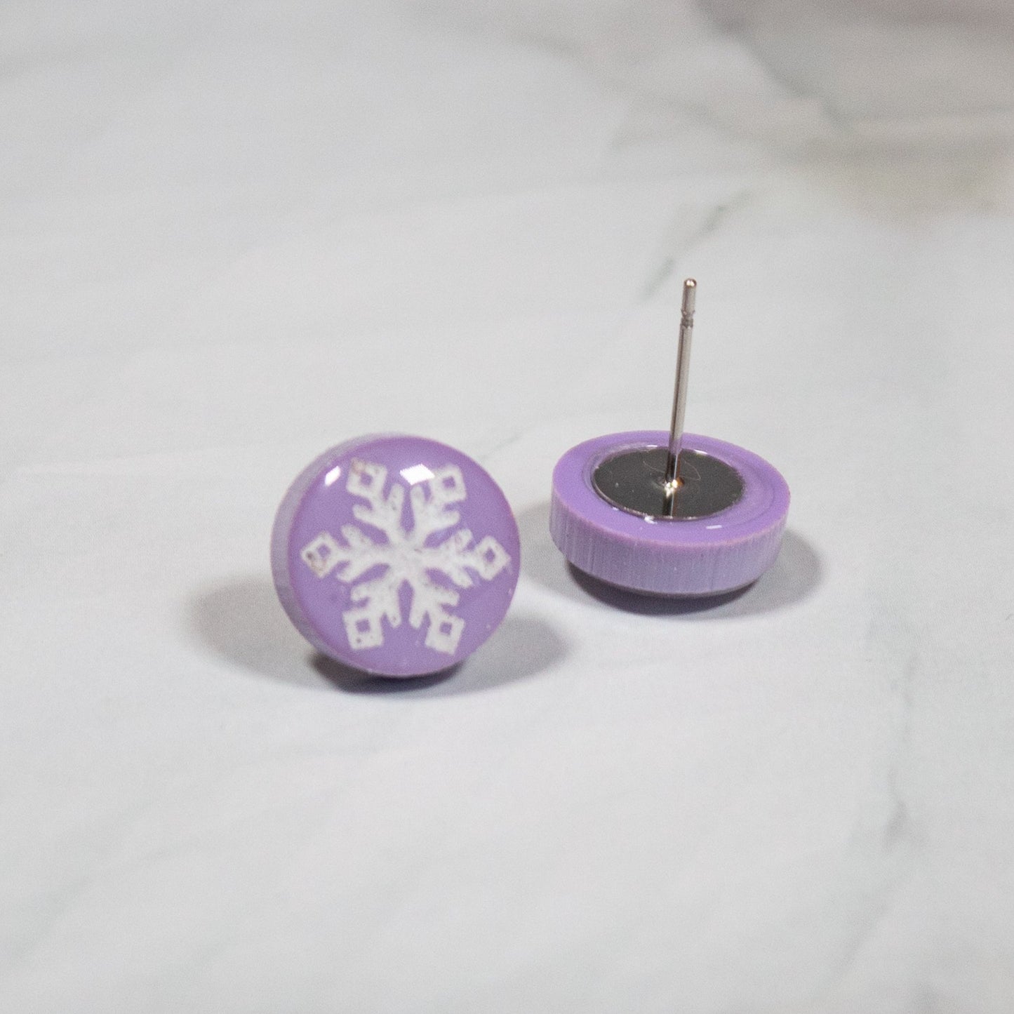 light purple circular studs with white snowflake design on white marbled background