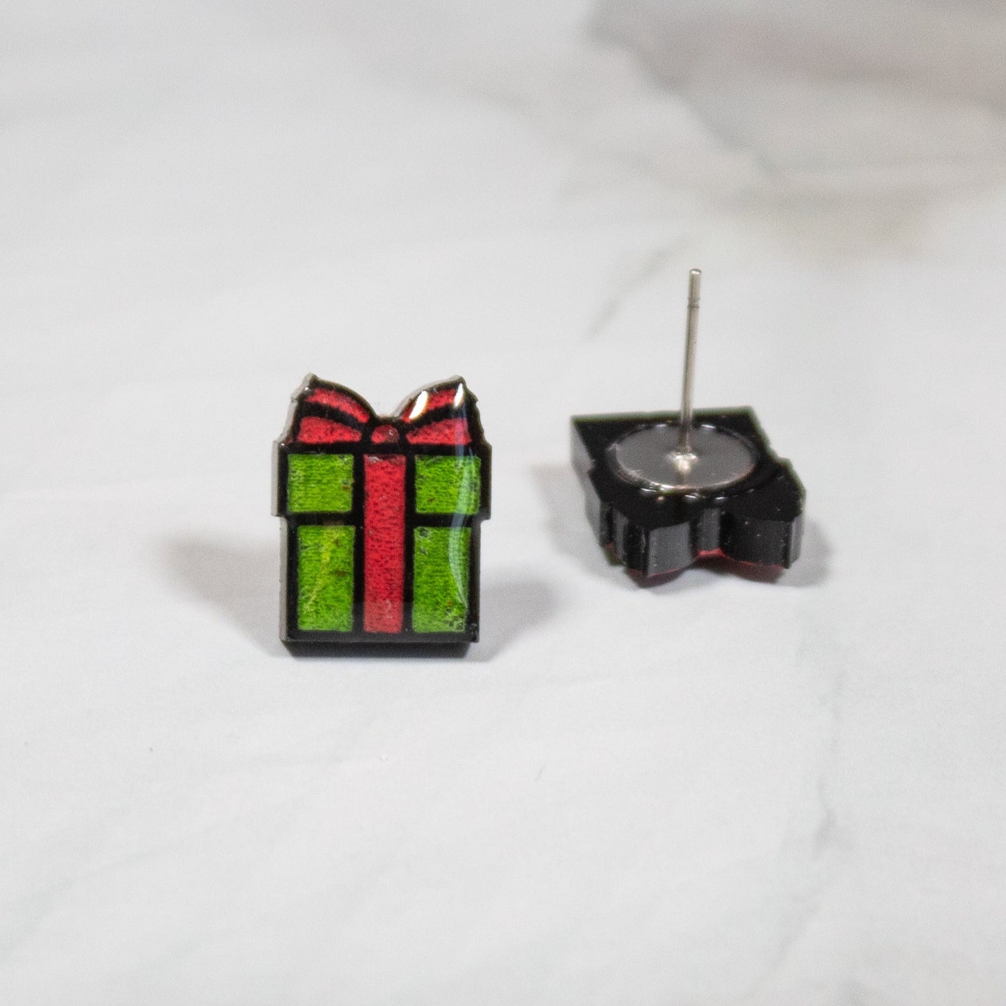 vibrant red and green christmas gift stud earrings on white marble background