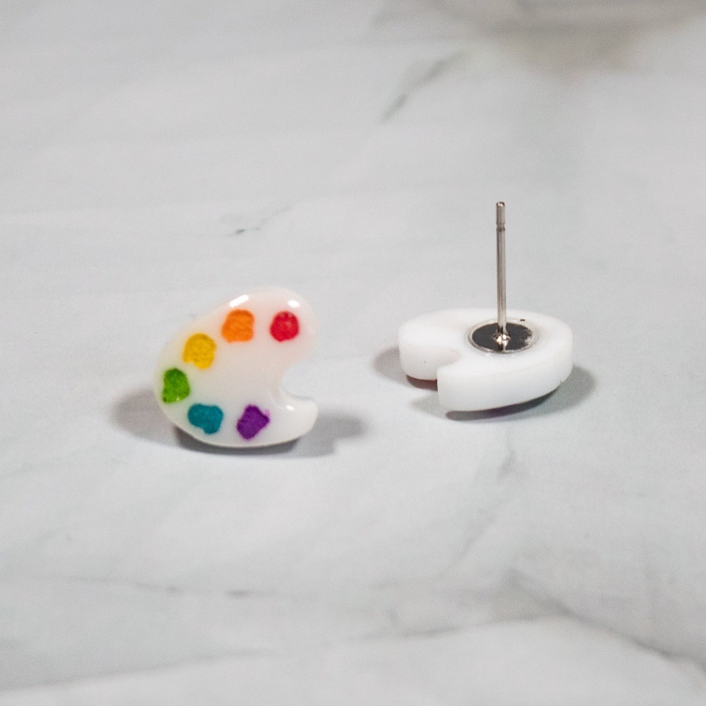 white artist pallet stud earrings with rainbow paint on white marble background