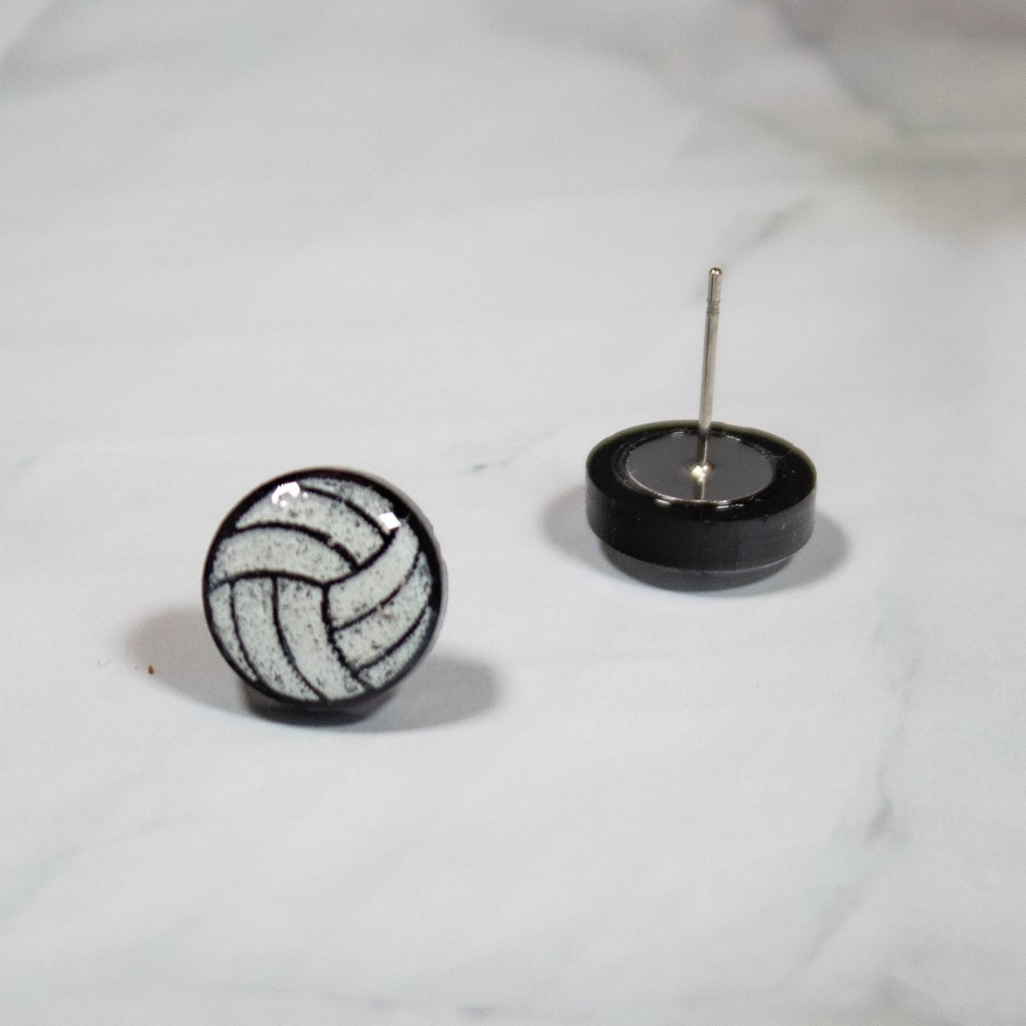 black and white volleyball stud earrings on white marble background