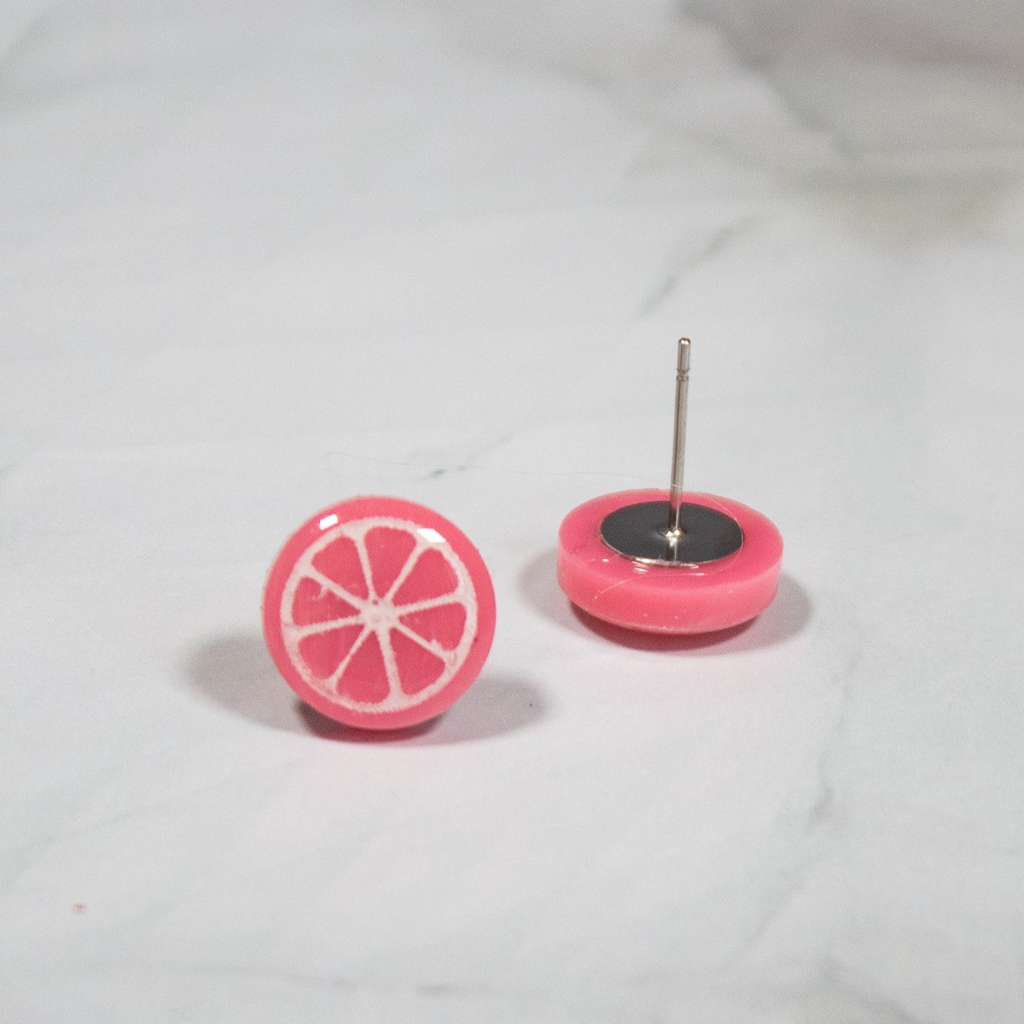 vibrant pink grapefruit style stud earring on white marbled background
