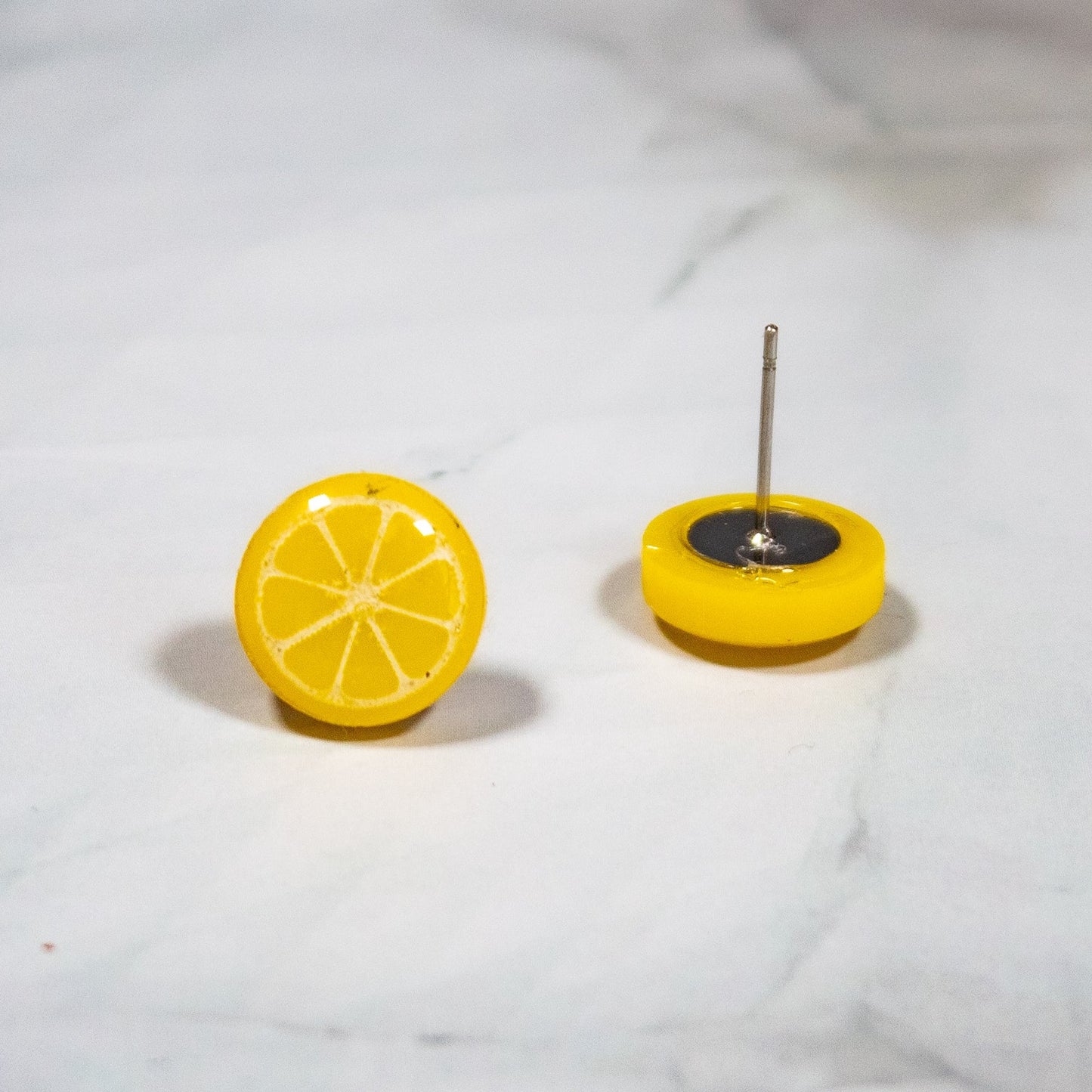 vibrant yellow lemon style stud earring on white marbled background