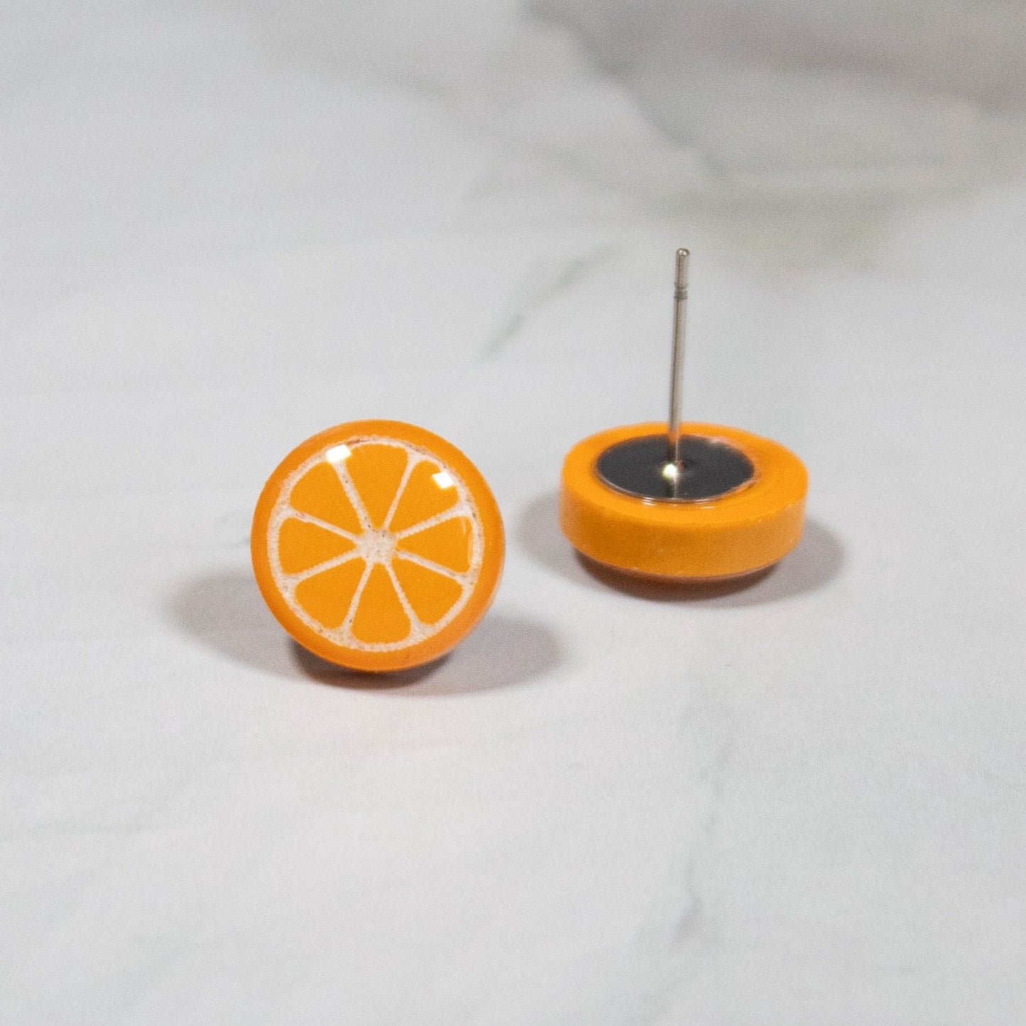 vibrant orange style stud earring on white marbled background