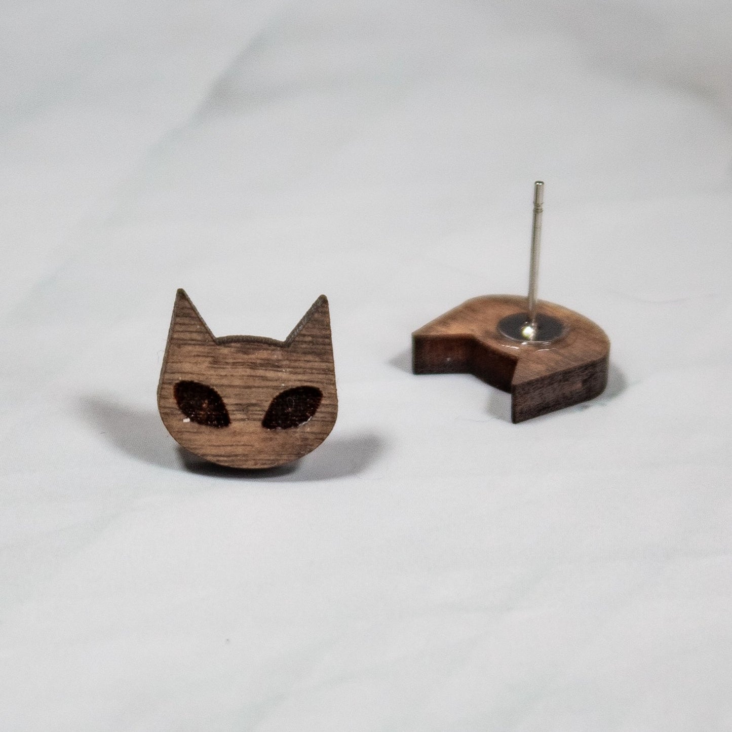 medium toned wood spooky cat stud earrings on white marble background