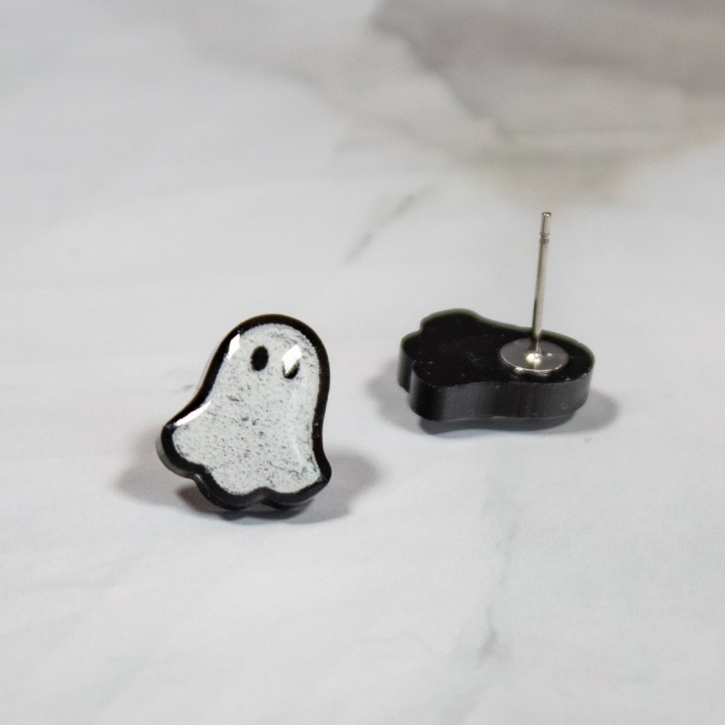 spooky black and white mini ghost stud earrings on white marble background