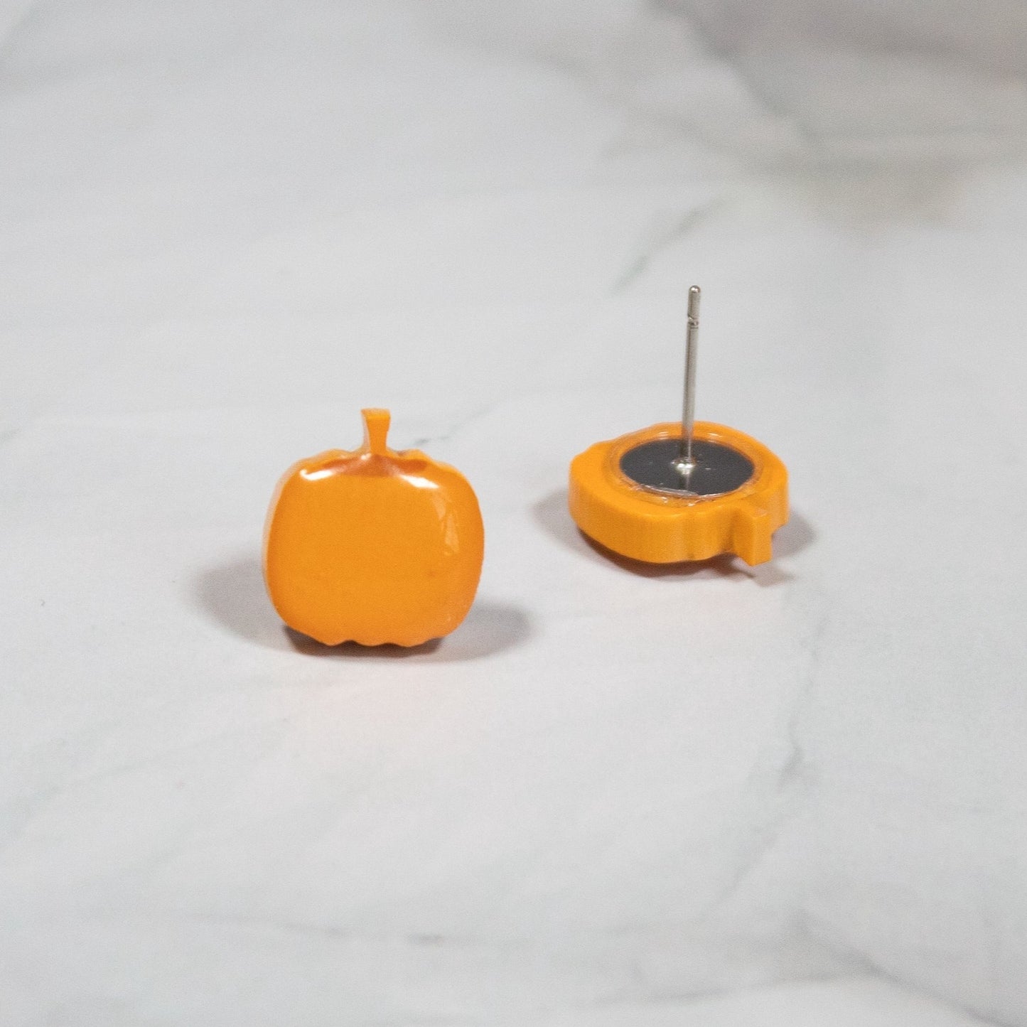 vibrant orange autumn harvest pumpkin stud earrings on a white marble background