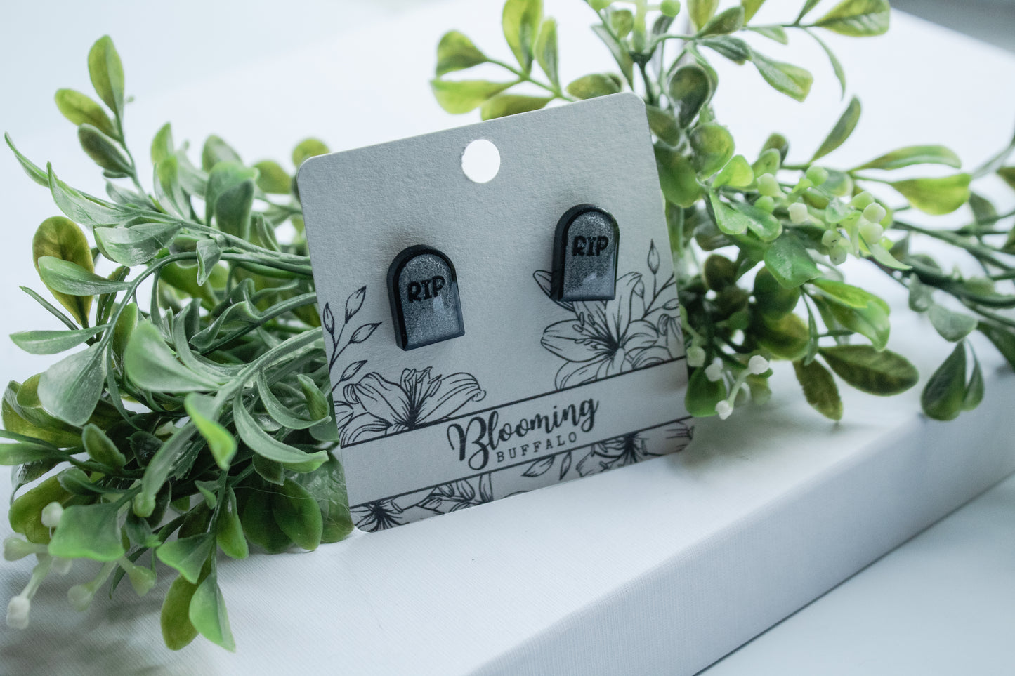 Gray and black tombstone stud earrings with RIP on Blooming Buffalo branded earring card
