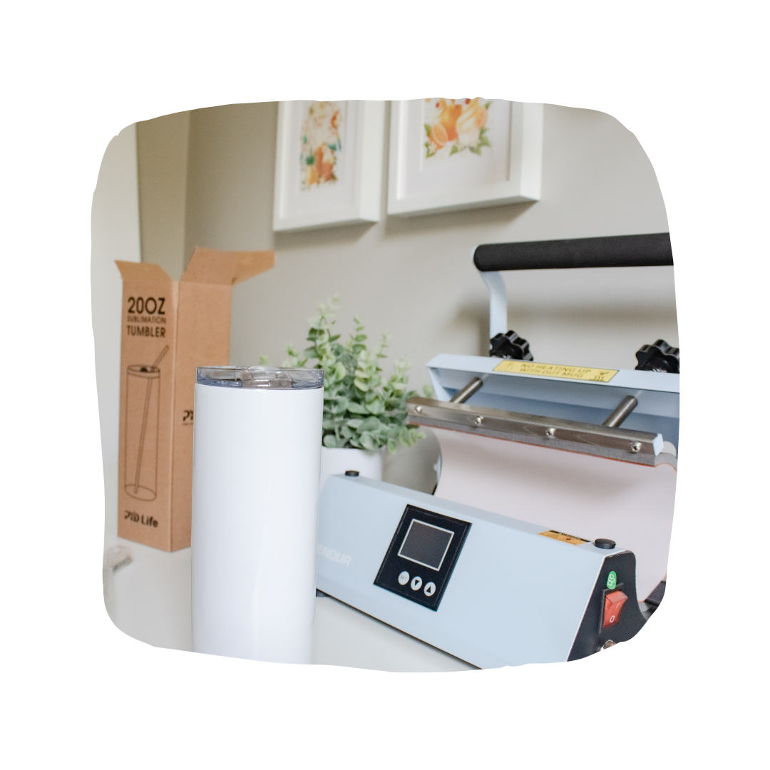 A bright work station featuring a heat press and a blank tumbler ready for sublimation.